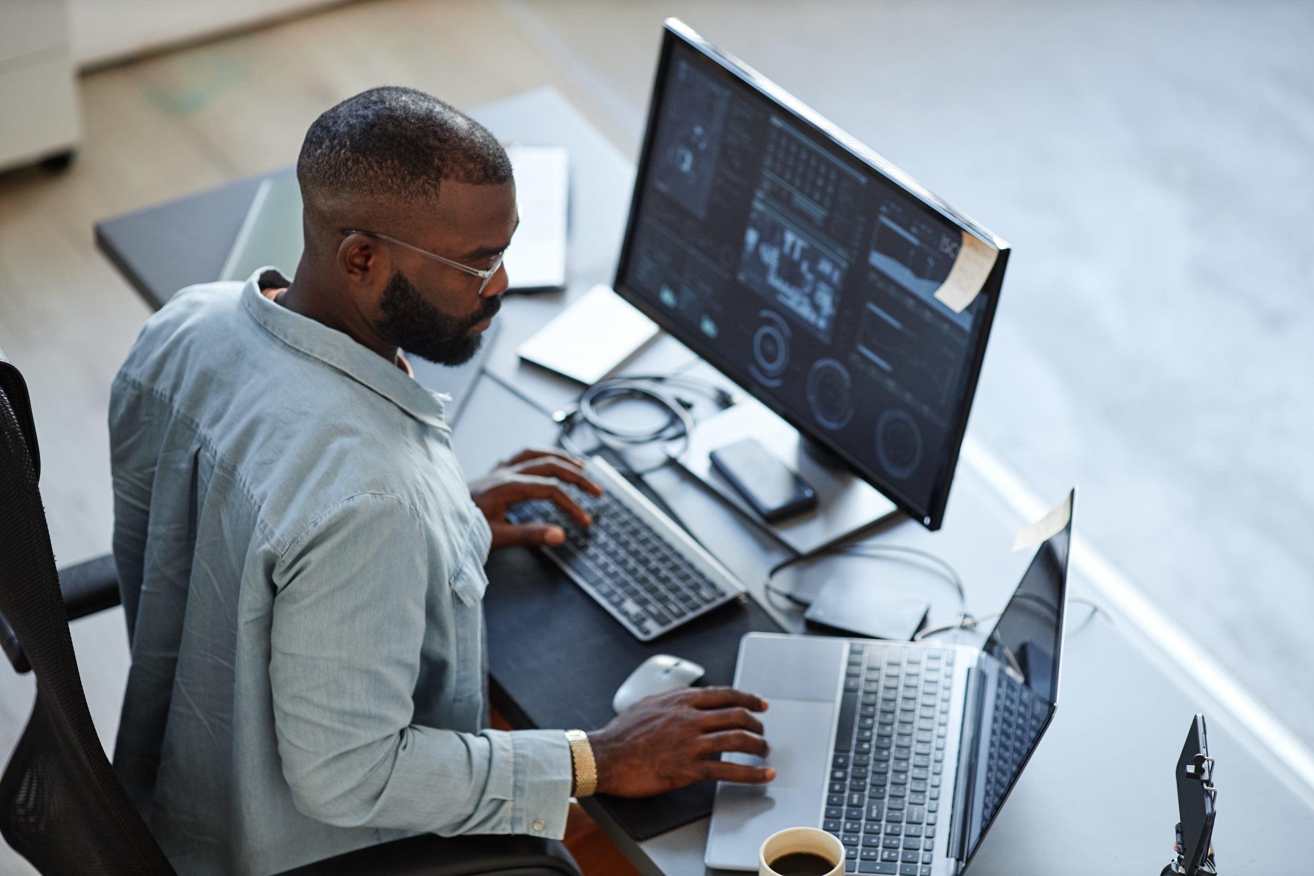 Man on laptop and monitor analyzing data